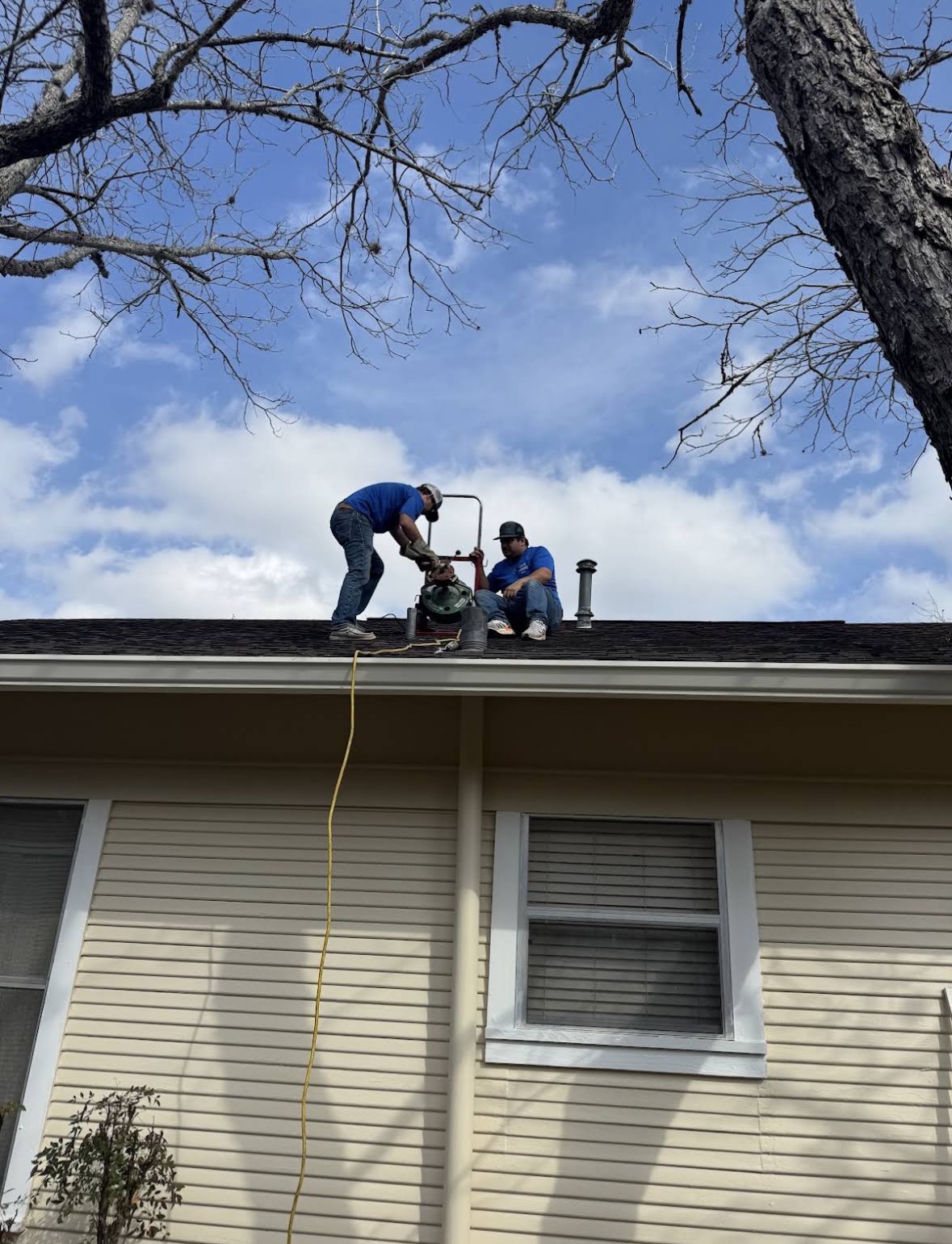 Technicians on roof clearing vent stack